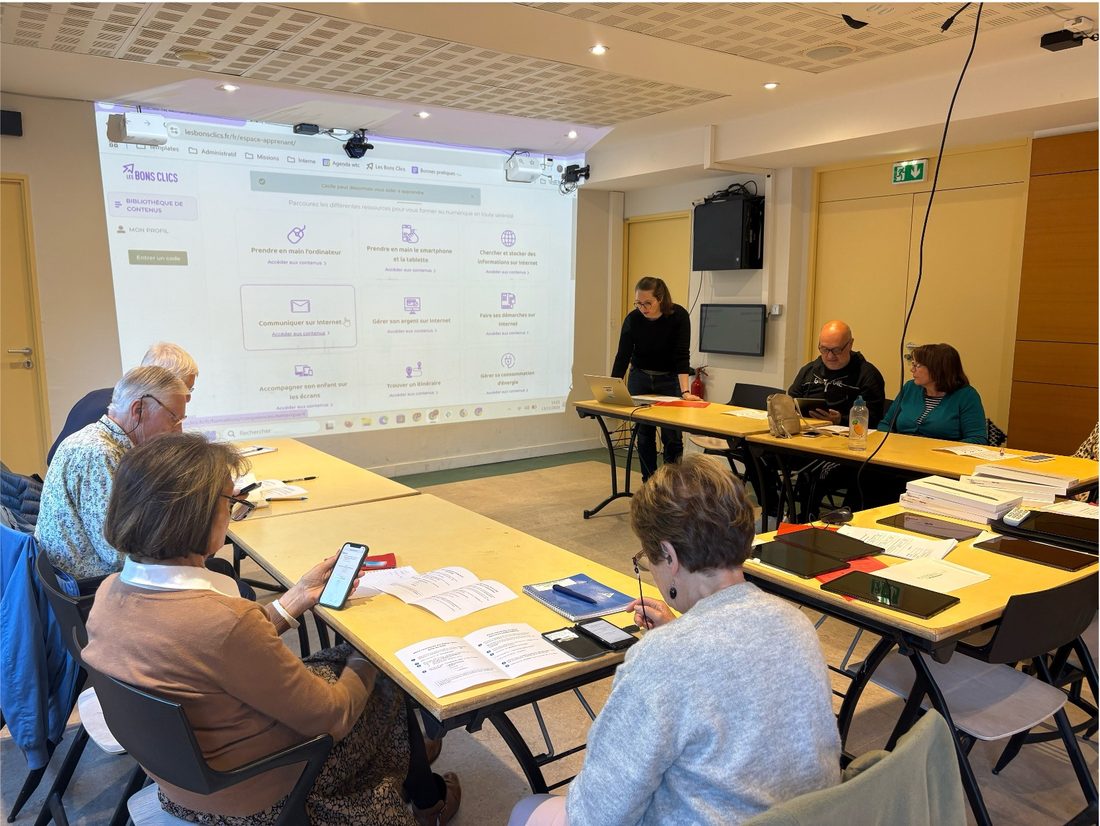 Une session de formation au numérique pour des seniors, accompagnés par un formateur autour de smartphones et de tablettes.